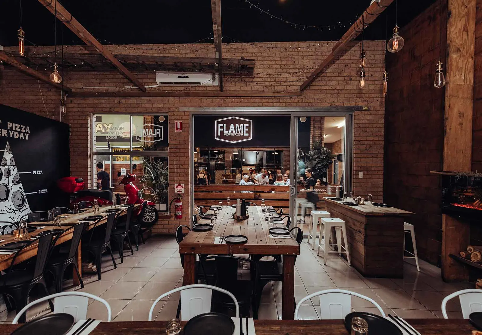Flame's dining room with exposed brick, timber tables and the neon Flame sign