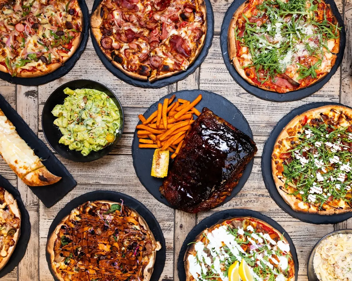 Woodfired pizzas, pork ribs, sweet potato fries and pastas on a timber table at Flame